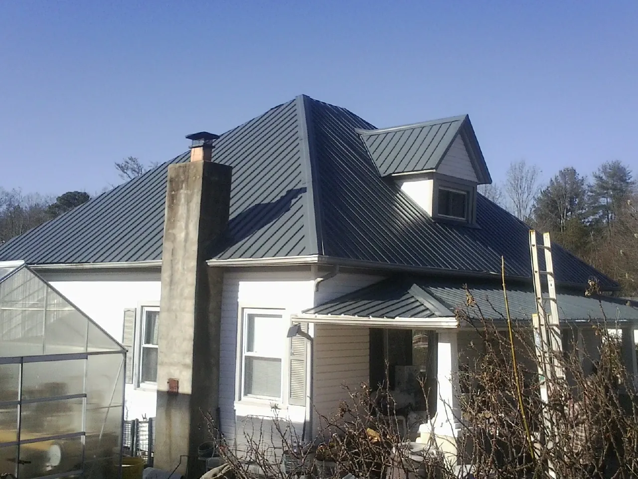 Dark blue standing seam metal roof on a white farmhouse with dormer — Slate & Tile Roof Repair by Roofing Brothers in Mangum