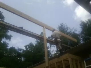 Carpenter setting a ridge beam over a new addition frame — Ice Dam Removal by Roofing Brothers in Mangum