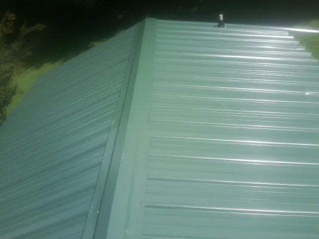 New green metal panels meeting at the ridge of a roof — Flat Roof Repair work by our crew in Mangum