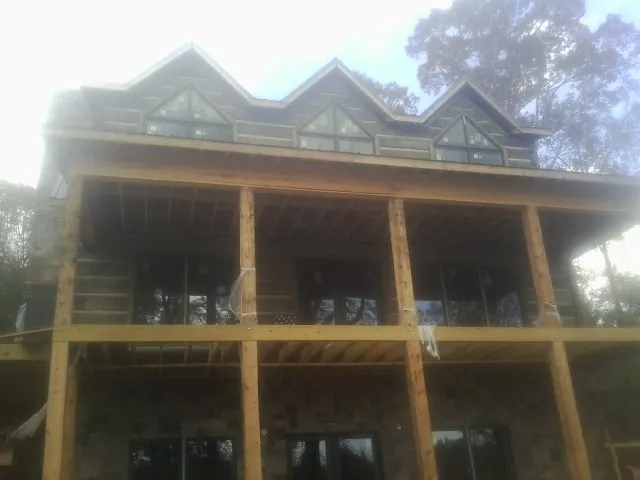 Dormers and porch framing on a large log home under construction — Roof Coating work by our crew in Mangum