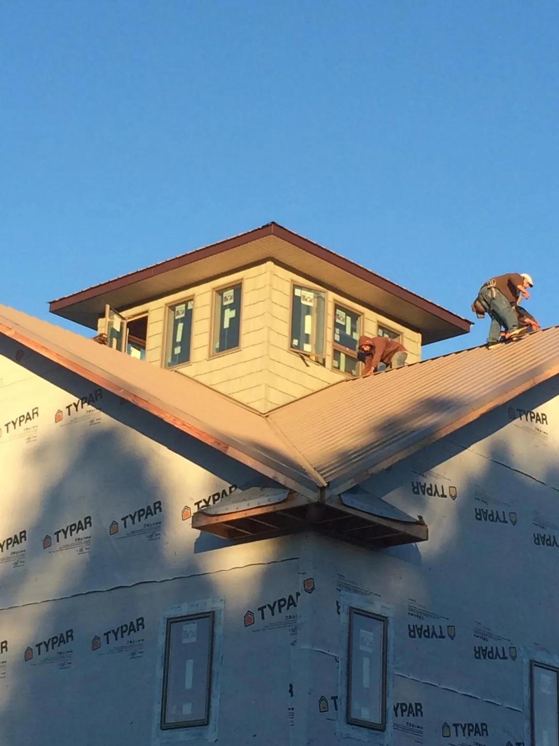 Roofers working around a rooftop cupola on a new metal roof at sunset — Roof Waterproofing in Mangum by Roofing Brothers